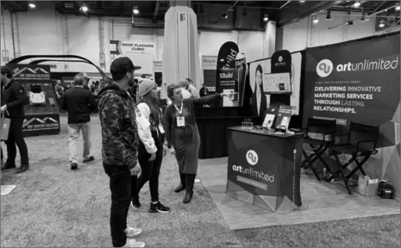 Michelle Lexvold talking with curious onlookers at Art Unlimited trade show booth 